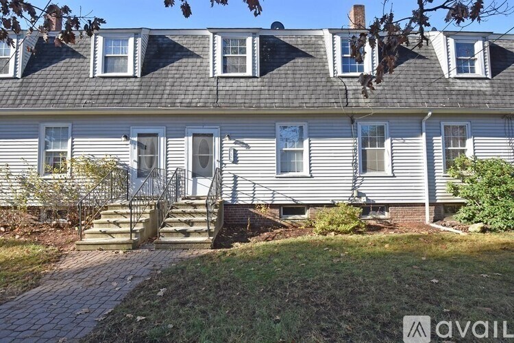 A house with a grey facade and a brown roof with white trim.