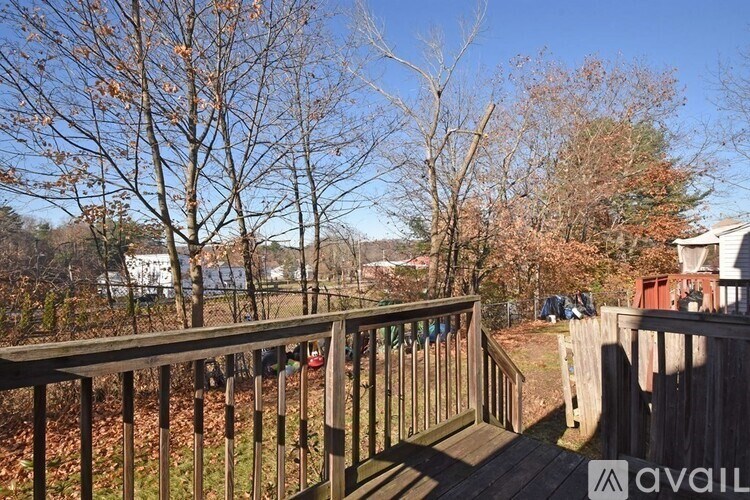 A deck with a railing and a view of a yard with trees.