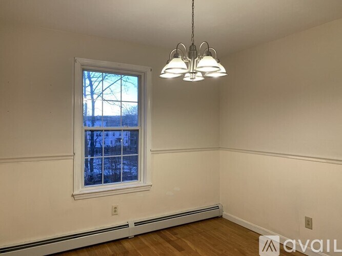 A room with a window and a chandelier hanging from the ceiling.