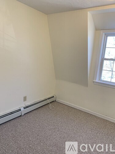 A room with a window and a carpeted floor.