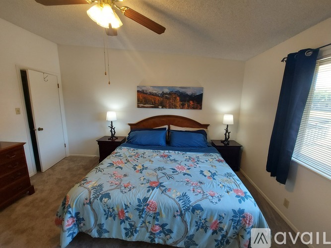 A bedroom with a floral bedspread and a ceiling fan.
