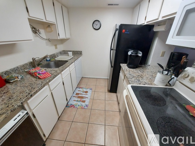 A kitchen with a black fridge and white cabinets.