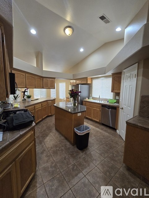 A kitchen with brown cabinets and a black trash can.
