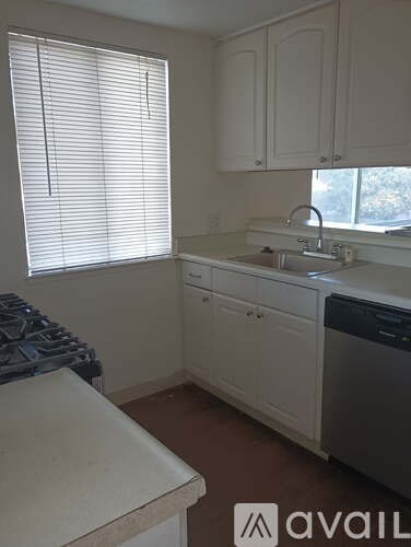 A kitchen with white cabinets and a stove top oven.
