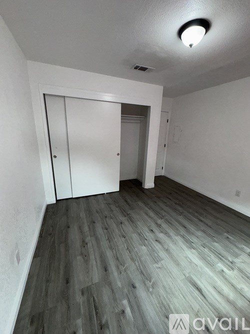 A room with a white door and wooden flooring.