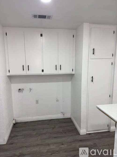 A room with white cabinets and a wooden floor.