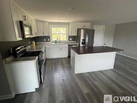 A kitchen with white cabinets and a black countertop.