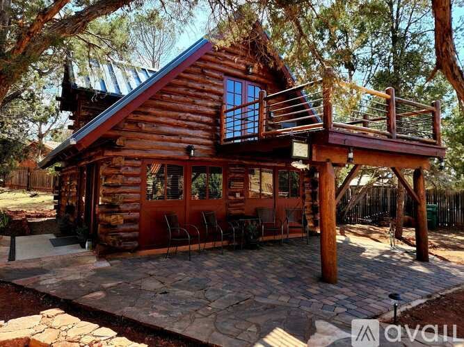 A wooden cabin with a balcony and a stone patio.