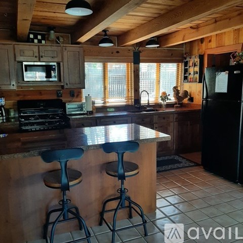 A kitchen with wooden cabinets and a black refrigerator.