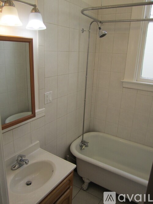 A white bathroom with a sink, mirror, and bathtub.