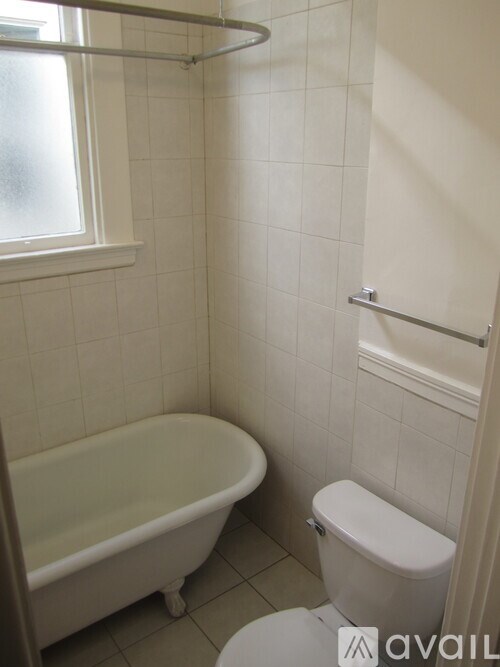 A white tiled bathroom with a toilet, tub, and shower.