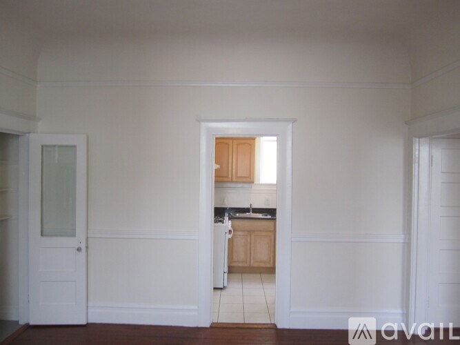 A kitchen area with a sink and cabinets is visible through an open door.