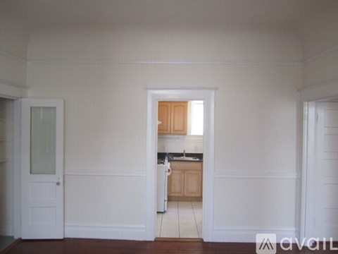 A kitchen area with a sink and cabinets is visible through an open door.