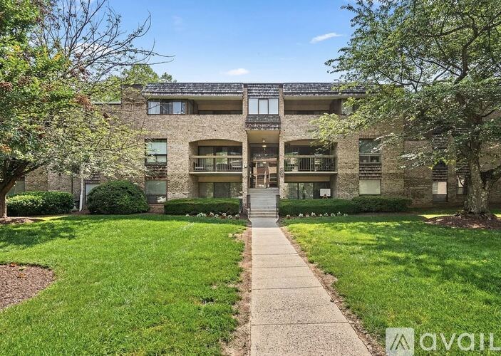 A building with a green lawn in front and a walkway leading to the entrance.
