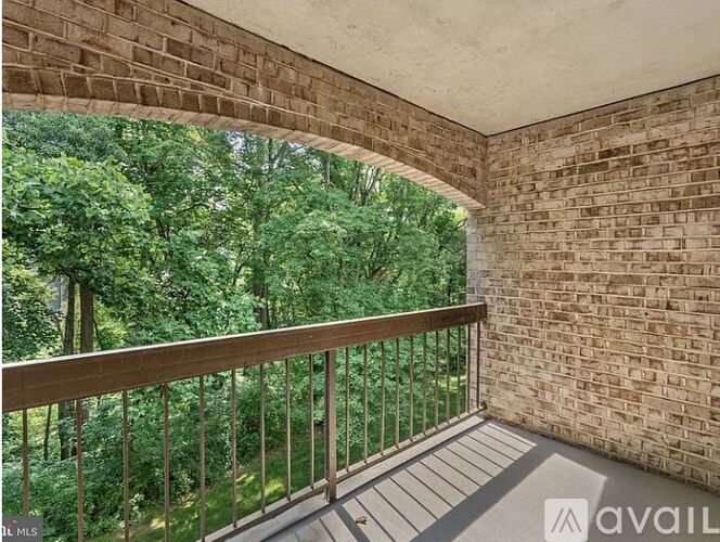A balcony with a brick wall and a metal railing overlooking a green forest.