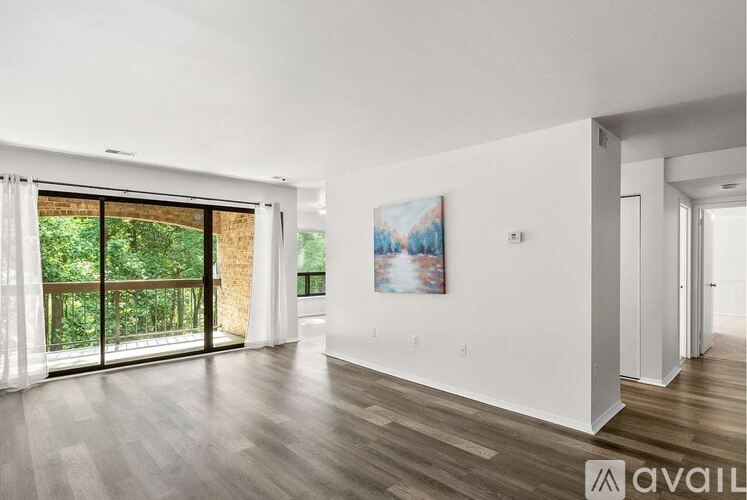 A spacious room with wooden floors and a painting on the wall.