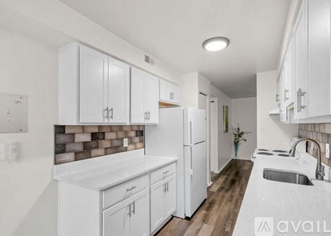 A kitchen with white cabinets and a brick backsplash.