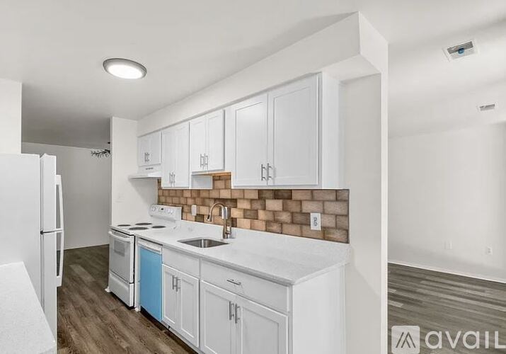A kitchen with white cabinets and a brick backsplash.