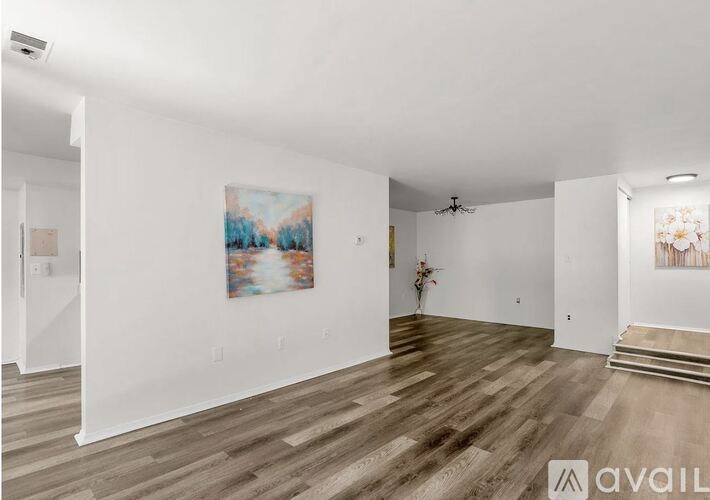 A spacious room with wooden flooring and a painting on the wall.