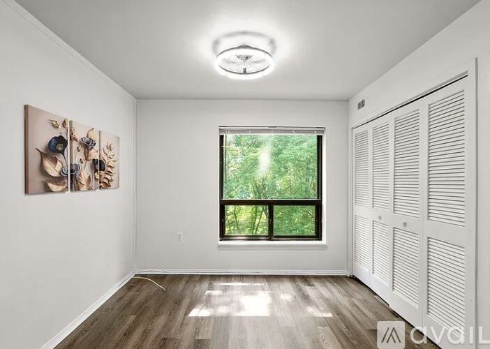 A room with a window and a painting on the wall.