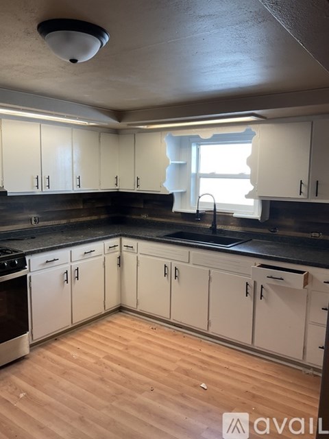 A kitchen with white cabinets and wooden floors.