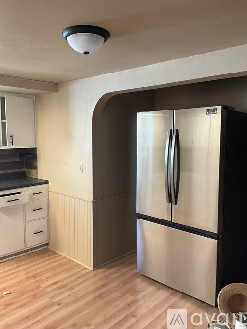 A black and silver refrigerator in a kitchen with wooden flooring.
