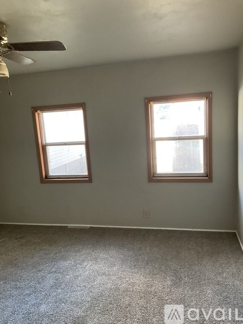 A room with two windows and a ceiling fan.