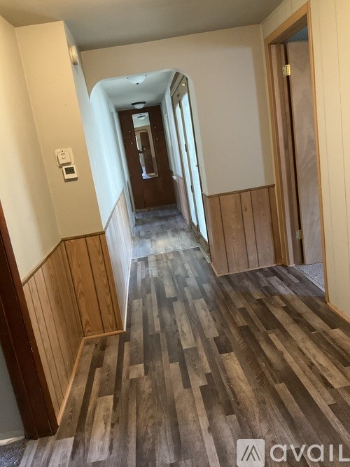 A hallway with wood flooring and white walls.