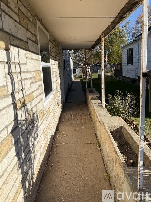 A long, narrow walkway with a brick wall on one side and a metal railing on the other.