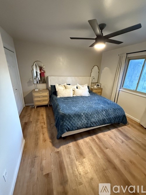 A bedroom with a bed, dresser, mirror, and window.
