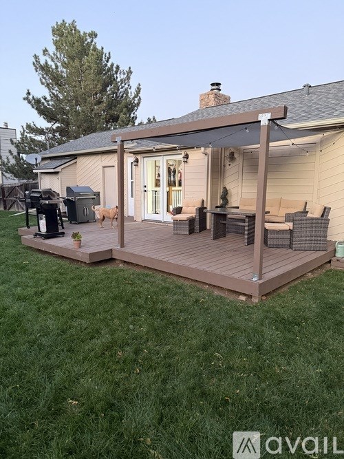 A covered patio with a table and chairs is set up on a lawn.