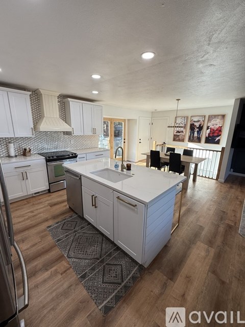A kitchen with white cabinets and a wooden floor.