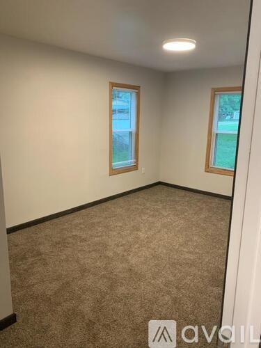 A room with carpeted floor and two windows.