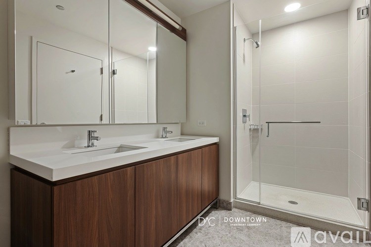 A modern bathroom with a double sink vanity and a walk-in shower.