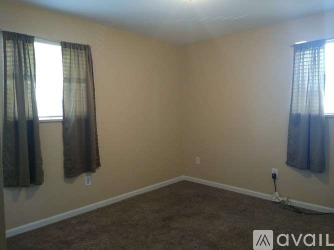 A room with two windows and a carpeted floor.