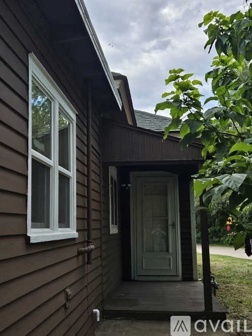 A brown house with a white window and a green door.