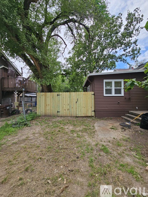 A backyard with a wooden fence and a tree.