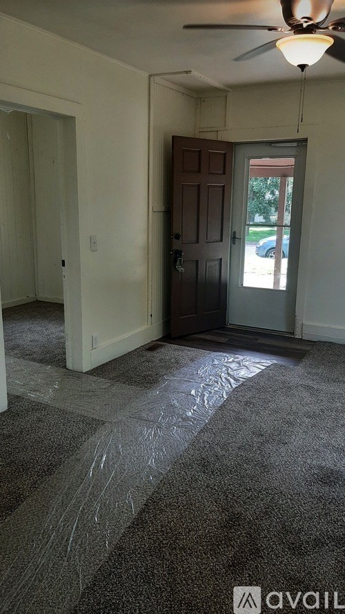 A room with a ceiling fan and a door leading outside.