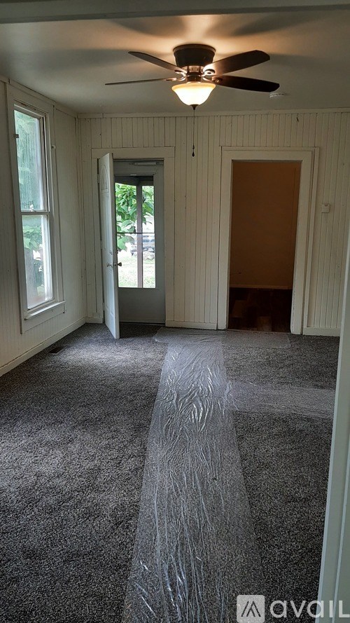 A room with a carpeted floor and a ceiling fan.