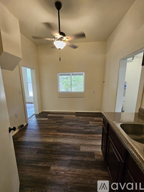 A kitchen with a wooden floor and a ceiling fan.