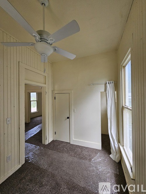 A room with a ceiling fan and a carpeted floor.