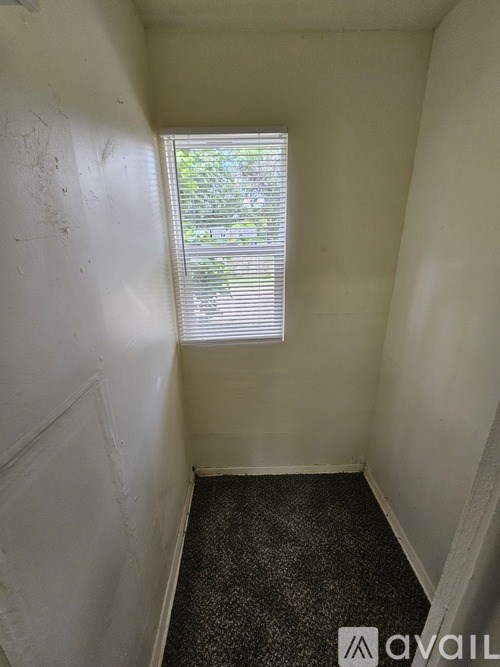 A small, empty room with a window and a carpeted floor.