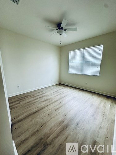 A room with a ceiling fan and wooden flooring.
