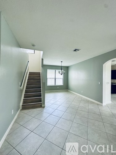 A spacious room with a staircase leading to the upper level.