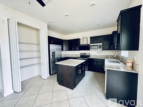 A kitchen with black cabinets and a white fridge.