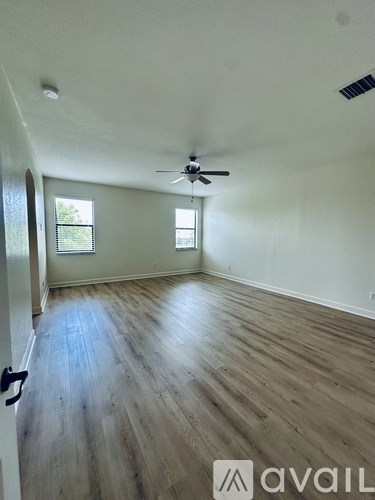 A room with wooden flooring and a ceiling fan.