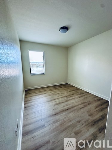 A room with wooden flooring and a window with blinds.