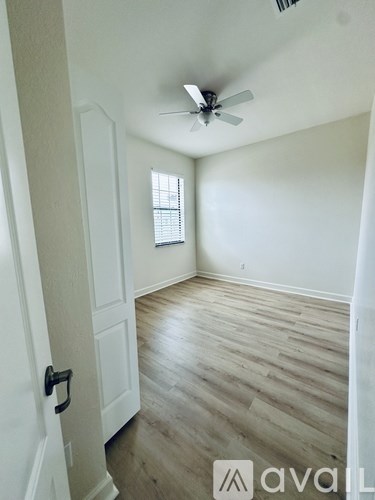 A room with a ceiling fan and a door with a handle.