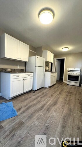 A kitchen with white appliances and wooden floors.
