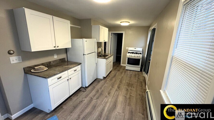 A kitchen with white cabinets and a wooden floor.